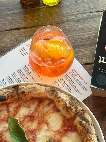 A close-up on a refreshing Aperol Spritz, the perfect summer drink to pair with any of our pizzas.