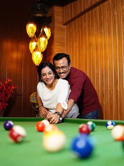 A fun and playful shot from a 25th-anniversary celebration, with the couple enjoying a game of pool together.