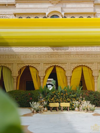 The couple's seating for the yellow-themed Haldi, set against the palace's ornate arches. The space was filled with lush greenery and marigolds, perfectly blending the vibrant theme with the royal architecture.