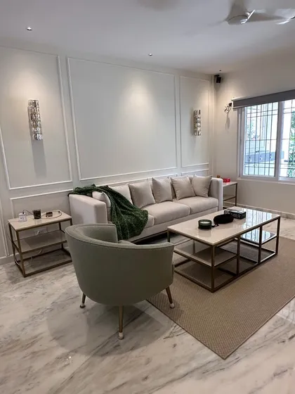 This living room, part of a complete residence we furnished, showcases a coordinated set of our work. The clean-lined sofa, marble-topped coffee table, and matching side tables create a harmonious and sophisticated atmosphere against the classic wall molding.