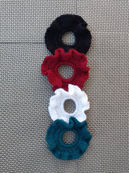 A flat lay of my crochet scrunchies in four different colors. I offer discounts for bulk orders of these.