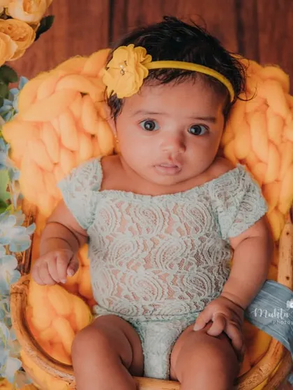 The bright yellow chunky knit and flowers make the perfect frame for this beautiful 3-month-old baby girl.