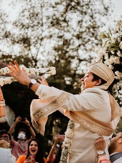 The fun and playful varmala exchange. Our simple and elegant white floral arch ensures that the focus remains on the couple's happy and emotional interaction.