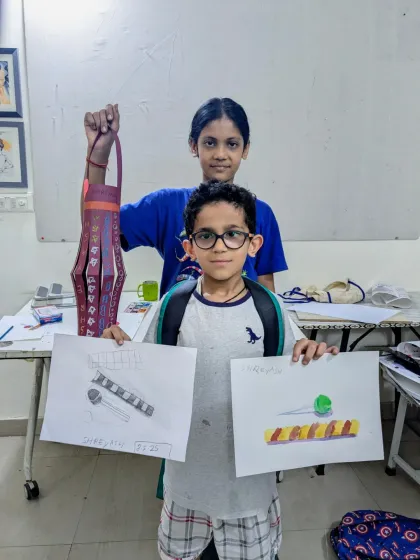 Two students from our junior batch proudly displaying their work from an object study class and a craft session.