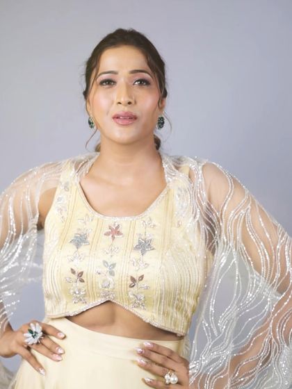 A confident pose in our pastel yellow lehenga. This shot highlights the modern cut of the blouse and the shimmering, sheer cape sleeves, perfect for a fashion-forward wedding guest.