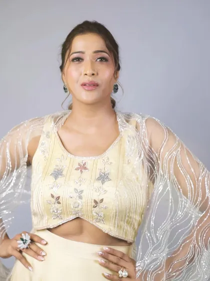 A confident pose in our pastel yellow lehenga. This shot highlights the modern cut of the blouse and the shimmering, sheer cape sleeves, perfect for a fashion-forward wedding guest.