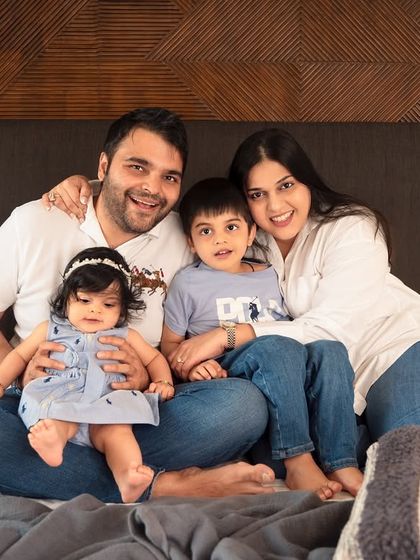 A classic family portrait taken during an in-home session. Sitting together on the bed, this family's comfort and connection are clear, making for a relaxed and natural photo.