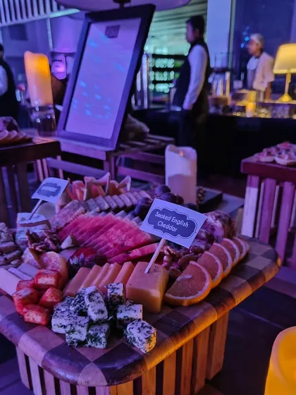 A beautifully arranged cheese and fruit board at the Mercedes EQ launch. This checkerboard-patterned board includes smoked English cheddar, fresh oranges, and various other cheeses, creating a visually stunning and delicious offering.