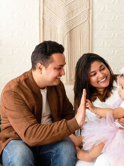 A playful high-five between parents and their baby. I use fun prompts to create natural smiles and interactions during family shoots.