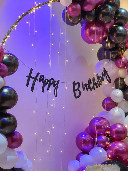 The fairy lights and 'Happy Birthday' banner inside the balloon ring create a magical focal point for this home celebration.