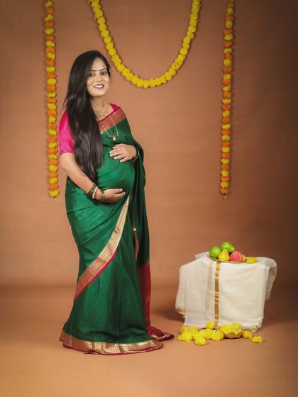 A portrait of a glowing mother-to-be. Dressed in a beautiful green saree, she looks so serene and happy in this traditional maternity photoshoot setup.