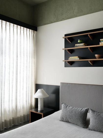 A view of the son's bedroom, showing the striped headboard and custom black bedside table. I design furniture to reflect the user's personality while maintaining a calm and organized environment.