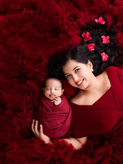 The bond between a mother and her newborn is pure magic. For this shot, we used a flowing red gown and fabric to create a rich, warm bed, capturing a beautiful smile from the little one.