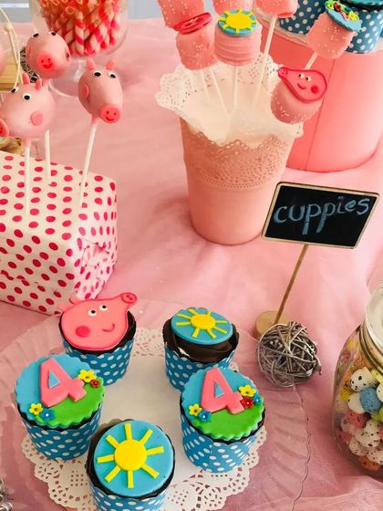A colourful Peppa Pig themed dessert table for a 4th birthday. Featuring custom cupcakes and piggy cake pops, this setup is designed to bring your child's favourite cartoon to life.