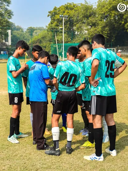 A team huddles up with their coach for a tactical discussion, a great example of communication and teamwork.
