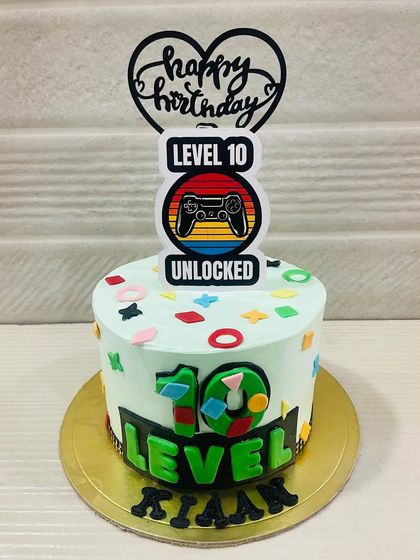 "Level 10 Unlocked." A cool cake for a young gamer, featuring a controller and colorful game-inspired decorations.