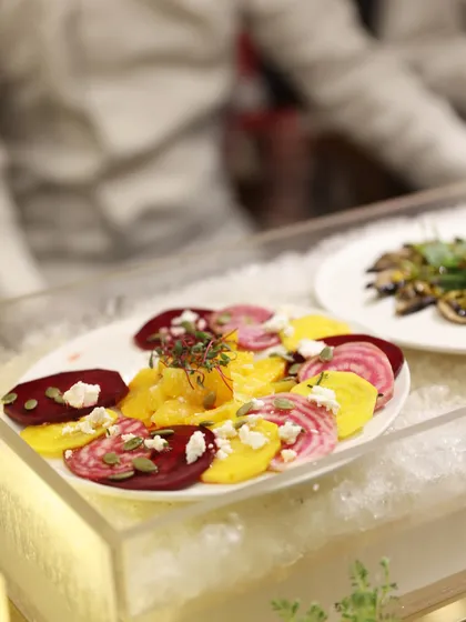 A colourful salad of sliced heirloom beetroots and oranges with feta, presented on a bed of crushed ice in a clear acrylic box for a stunning visual effect.