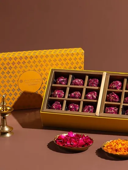 A box of rose-petal-covered chocolates, part of the Pullman New Delhi Aerocity's festive collection. The minimalist styling emphasizes the elegance of the product.