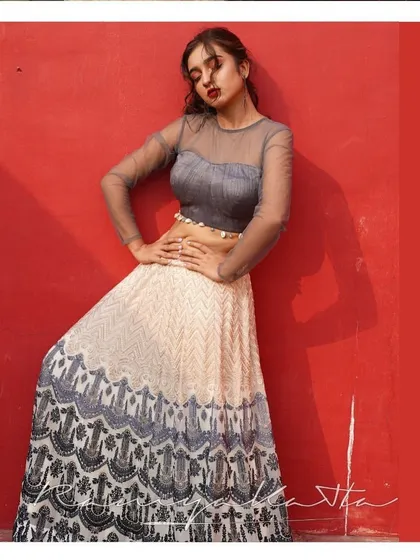 A chic and modern lehenga in grey and cream georgette. The skirt features intricate threadwork, paired with a stylish tulle crop top with shell detailing for a beach wedding or cocktail party.