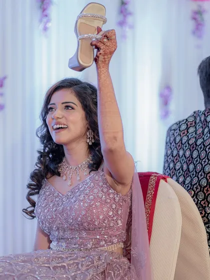A fun, candid moment from the sangeet ceremony, with the bride holding up the groom's shoe.