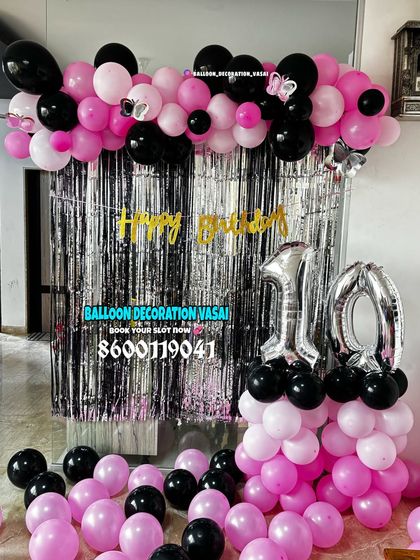 A 10th birthday decoration in pink and black. The silver shimmer curtain and foil number balloons add a touch of glam.