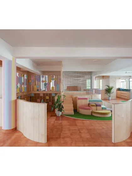 For the 'Nivriti' playschool, we designed the entire space from a toddler's perspective. The open play area features soft, artificial turf, modular seating in bright colors, and curved wooden partitions for safety.