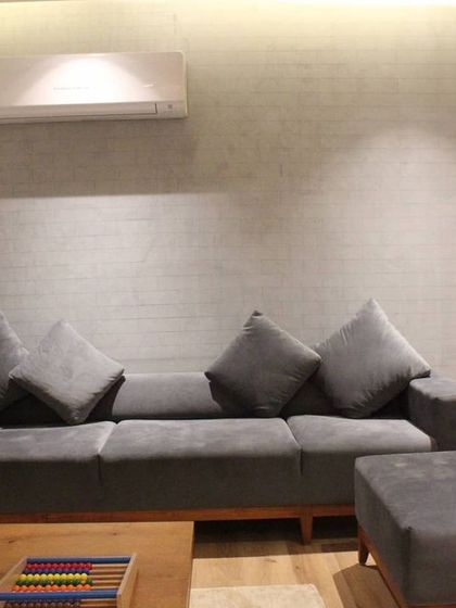 A custom-made grey sofa with a solid wood base, designed for another seating area in the Hyderabad residence. The simple, modern form provides comfortable and stylish seating.
