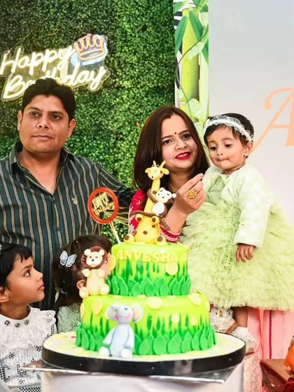 The cake cutting ceremony at a Jungle Safari party. Our decor provides the perfect setting, with a themed cake, a 'Happy Birthday' neon sign on a grass wall, and character props.