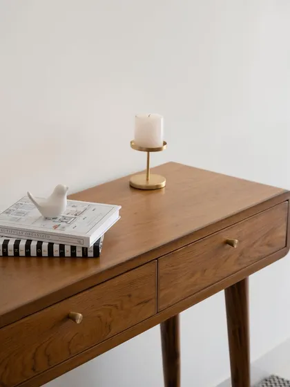 A close-up of the 'Marshall' console table, focusing on the curved drawer front and the minimalist brass knob.