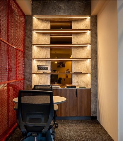 Another view of the collaborative nook, highlighting the backlit shelving and the mix of textures from the concrete-finish walls and wood cabinets. It's a functional and aesthetically pleasing corner.