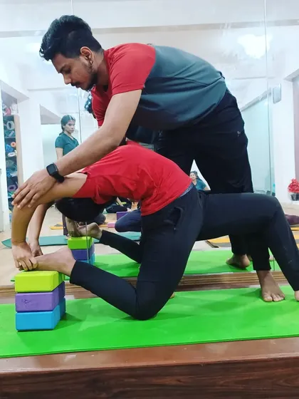 An instructor assists a student with a block-supported backbend. This personalized attention ensures the pose is both challenging and safe, targeting specific areas for improvement.