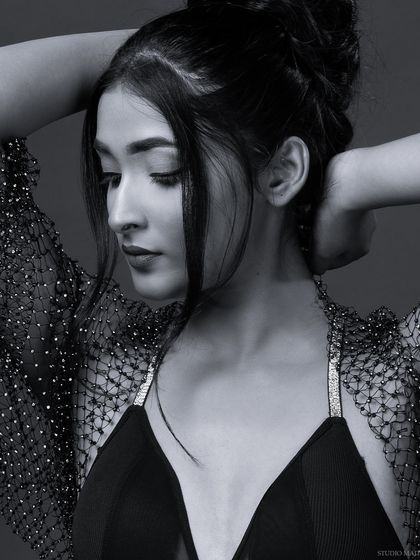 A pensive black and white portrait with an updo hairstyle. The monochrome style brings a quiet, introspective mood to this fashion shot.