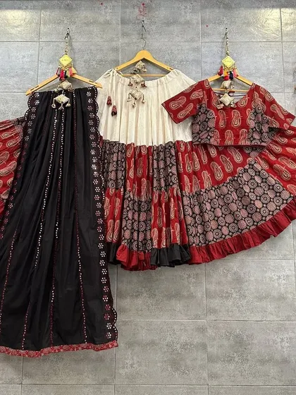 A playful and stylish red, black, and white chaniya choli. The tiered skirt and printed blouse create a fun and modern silhouette.