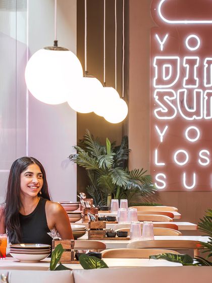 We strategically placed neon signage to highlight the restaurant's specialties, like dim sum. Here, a guest dines under the soft glow of pendant lights, with the playful sign creating a fun and Instagrammable backdrop.