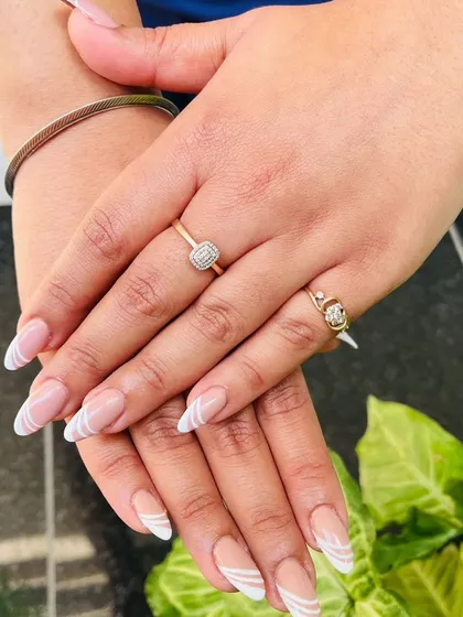 Here is a modern twist on the classic French tip, with clean white swirls on a natural nude base. This design is perfect for an everyday look that is still chic and eye-catching.