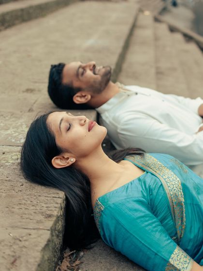 A serene portrait of the couple resting on the stone steps, a quiet moment of togetherness during their traditional pre-wedding shoot.