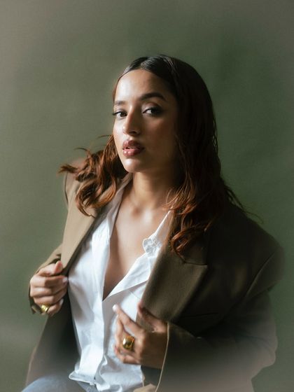 A confident and stylish portrait. The way the model holds the blazer adds a touch of casual elegance, while the soft lighting enhances the overall sophisticated feel.