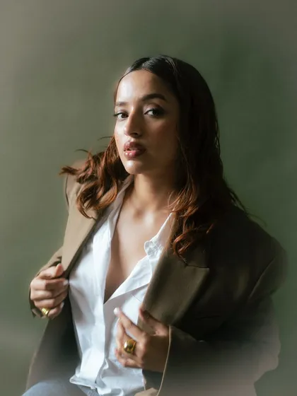 A confident and stylish portrait. The way the model holds the blazer adds a touch of casual elegance, while the soft lighting enhances the overall sophisticated feel.