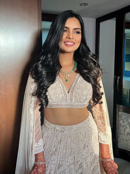 The Roka bride's full look, her hair styled in beautiful, flowing waves.