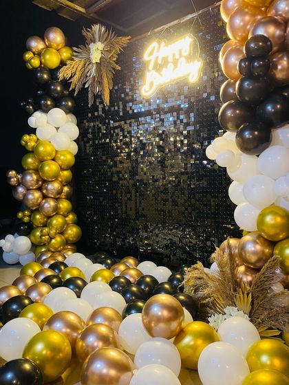 A low-angle shot of the glamorous black and gold birthday decor, with balloons covering the floor.