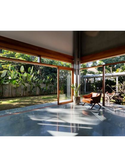 The main living space opens completely to the garden, with polished floors reflecting the greenery and blurring the line between indoors and outdoors.