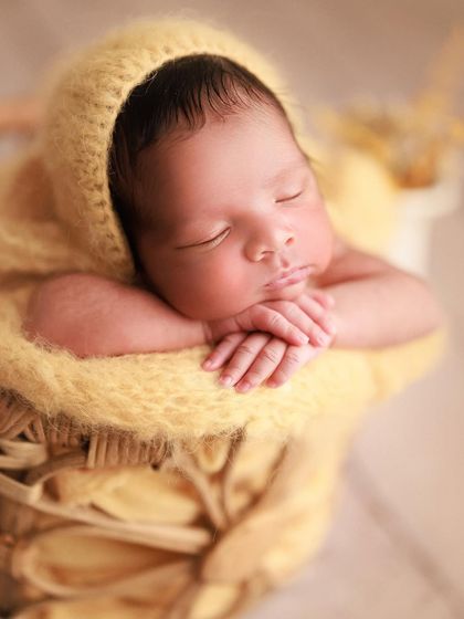 Wrapped in sunshine and love. This close-up shot focuses on the baby's serene expression, with their hands gently tucked under their chin.