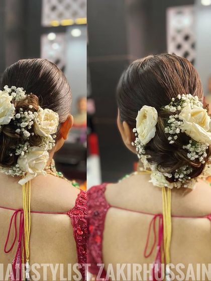 A traditional bridal bun surrounded by fresh white roses and baby's breath. This is a timeless and elegant choice for any bride on her wedding day.