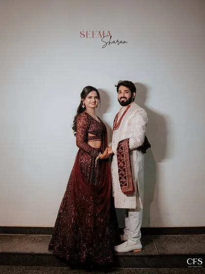 A classic, full-length portrait of a couple in their engagement outfits. The simple background puts the focus on their coordinated style and happy smiles.