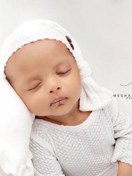 A close-up of the baby's face, resting on a soft white pillow.