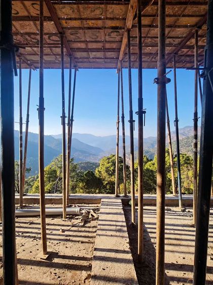The forest of support props inside the structure frames a stunning view of the valley, illustrating the open-plan design. Even in its raw state, the connection between the interior space and the vast landscape is clear.