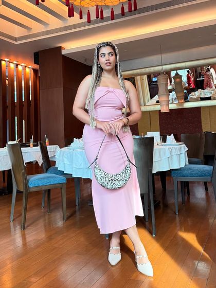 A full-length shot of the braided look. The sleek, long braids contrast with the soft, feminine silhouette of the pink dress, creating a really interesting style.