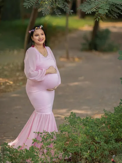 A beautiful solo portrait of a mom-to-be in a fitted pink gown, surrounded by the natural beauty of the park.