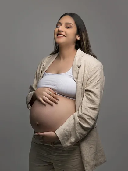 A candid, happy moment during the maternity shoot. Her subtle makeup look appears fresh and effortless, perfect for capturing these precious memories.