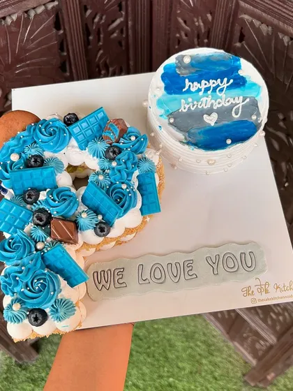 This set shows how you can pair a larger monogram cake with a matching bento cake. The letter 'P' cake and the mini cake are both done in a blue and white theme, perfect for sharing a heartfelt message like 'We Love You'.